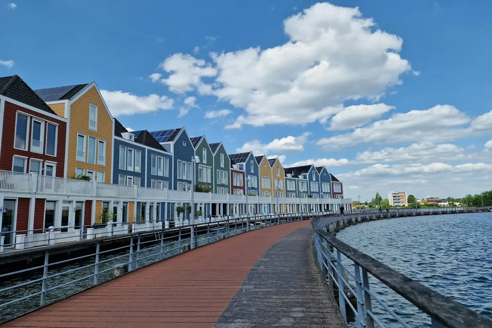 Een rij kleurrijke huizen aan het water in Houten, met zonnepanelen op een deel van de daken